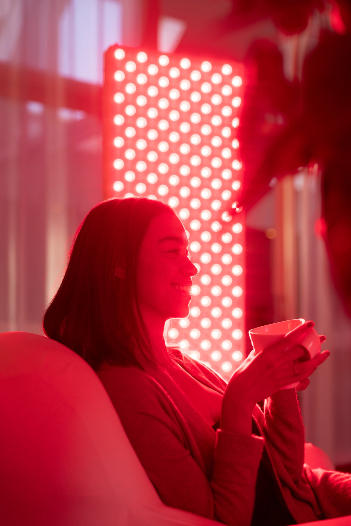 Woman sitting in an armchair with a cup of tea in front of the lit The Red Kangaroo