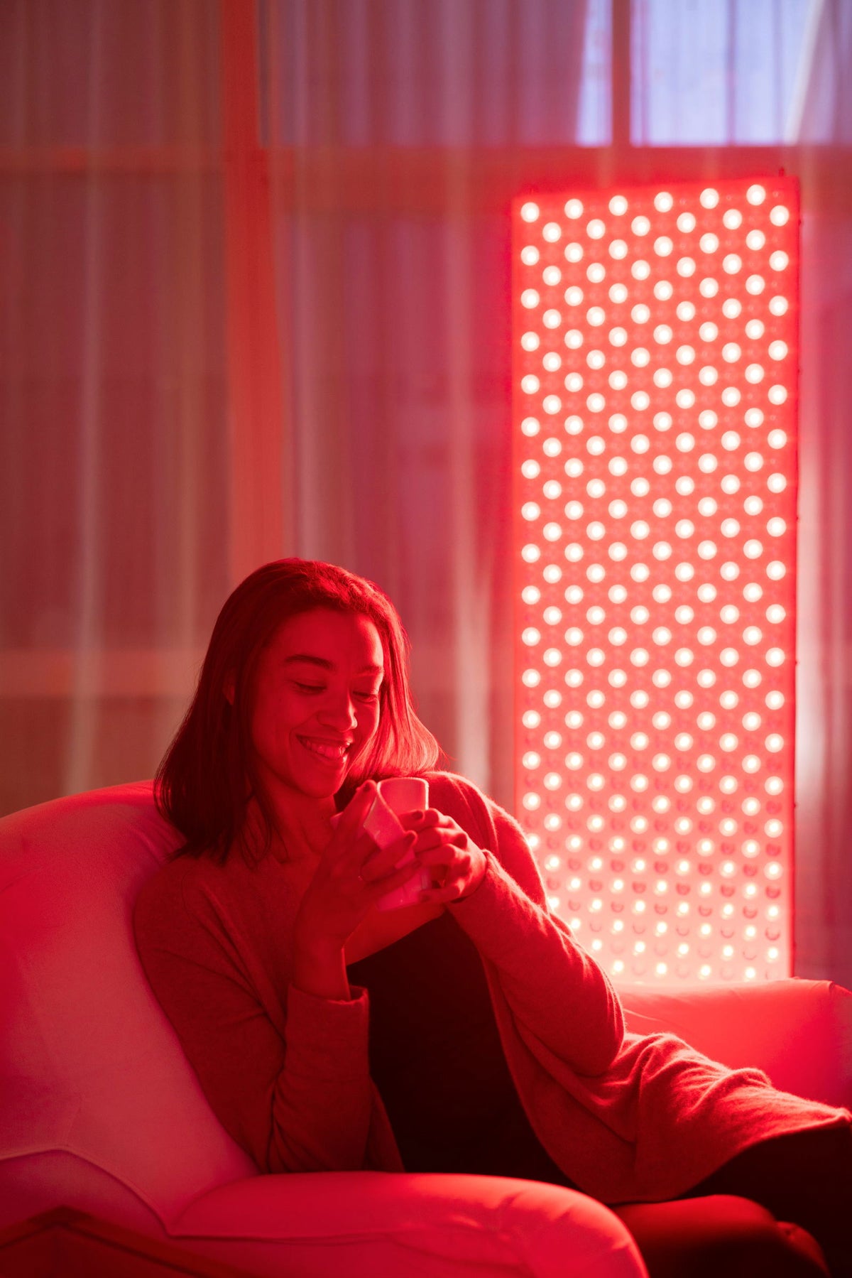 Woman sits relaxed in an armchair with a cup in front of the lit The Red Kangaroo.