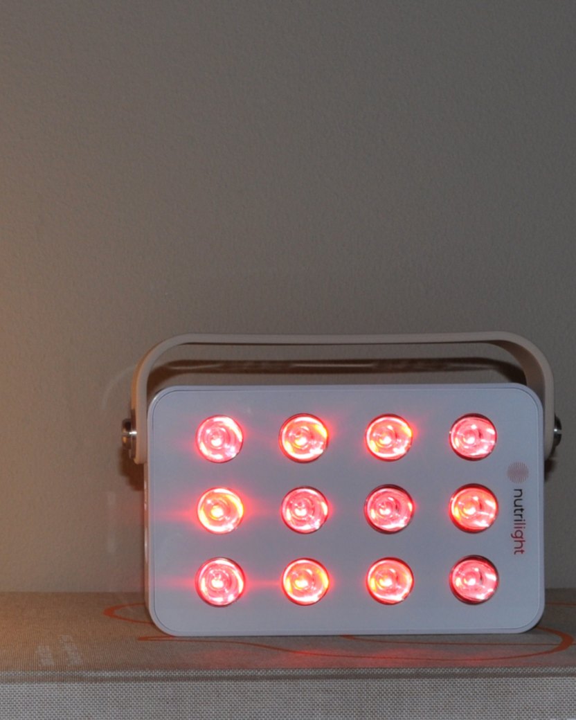 Robin Gen 2 lyser rødt på en bogreol ved siden af en lampe